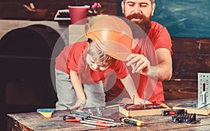 Father, parent with beard teaching little son to use different tools in school workshop. Boy, child busy play with