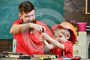 Father, parent with beard teaching little son to use tool screwdriver. Teamwork and assistance concept. Boy, child busy photo