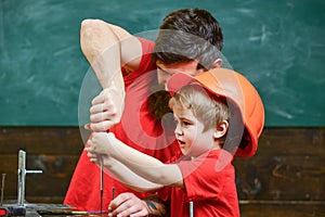 Father, parent with beard teaching little son to use tool screwdriver. Teamwork in workshop concept. Boy, child busy in