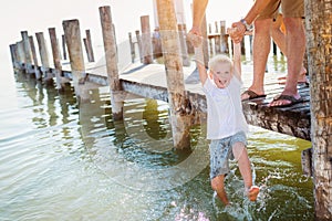 Father on the pier holding son above water, sunny summer