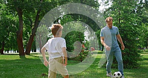 Father play football with son on green lawn closeup. Dad enjoy game with boy.