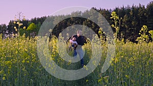 Father played with the baby in the rapeseed field and throws it Slow motion