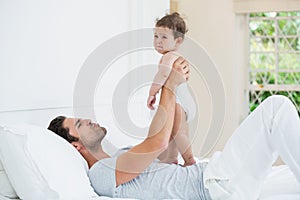 Father playing with crying daughter on bed