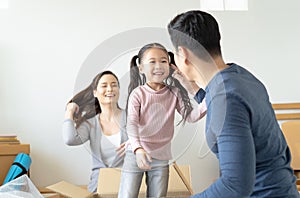 Father playing cute little daughter doing riding in cardboard boxes,  young Asian family kids having fun in new house living room