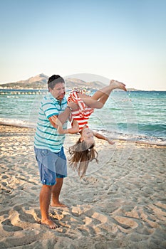 Father playing with his daughter on the evening beach