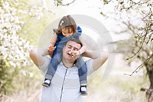 Father playing with his daughter in the park. Daughter sitting on father shoulders. Portrait of happy family. father`s, baby`s d