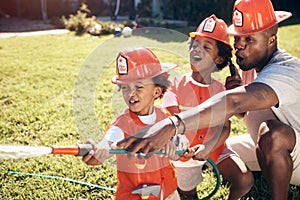 Father playing with his sons outside. Little boys dressed as firemen. African American boys playing outside. Brothers