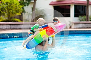 Kids on inflatable float in swimming pool.