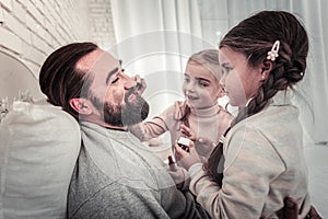 Father playing with kids by letting them paint his face