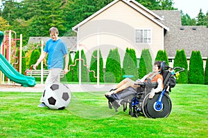 Father playing soccer with disabled son in wheelchai