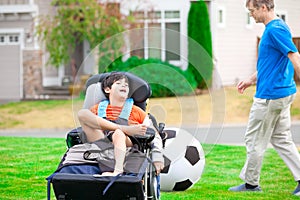 Father playing soccer with disabled son in wheelchai