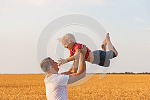 Father playing with son outdoors in field. Daddy tosses child up photo
