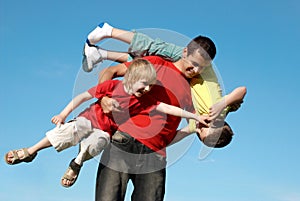 The father playing with sons against sky