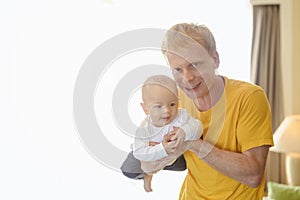 Father playing with toddler baby son having fun at home in holiday.