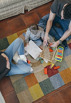 Father playing with toddler while the mother is looking at them