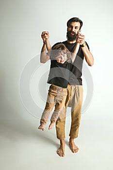 Father playing with young son against white studio background