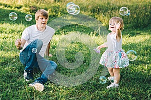 Father plays with his daughter with soapbubble