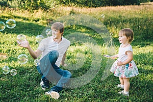 Father plays with his daughter with soapbubble