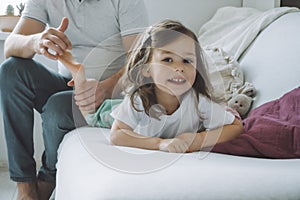 Father plays with little daughter 2-4 on couch. Dad tickles kids feet. Family, having fun