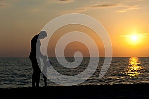 Father plays with son against a sunset