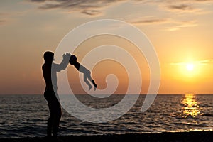 Father plays with son against a sunset