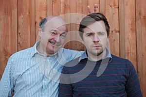 Father pranking his son with bunny ears on wooden background. photo