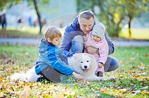 Father with preschool son and baby daugther playing with his samoyed dog photo