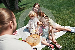 Father presenting a birthday cake to his little children. Family relaxing, having picnic in the park, celebrating child
