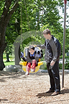 Father pushing disabled boy in special needs swing