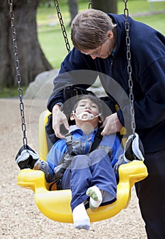 Father pushing disabled son on handicap swing