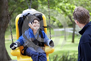 Father pushing disabled son on handicap swing