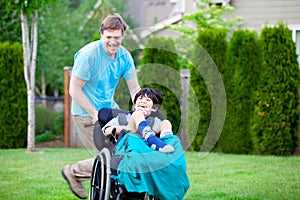 Father racing around park with disabled son in wheelchair
