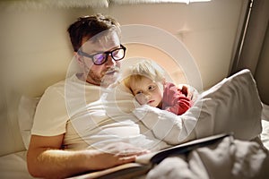 Father reading bedtime stories to child. Dad putting son to sleep