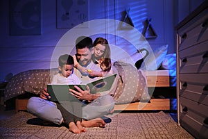 Father reading bedtime story to his children at home