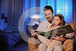 Father reading bedtime story to his daughter at home