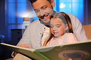 Father reading bedtime story to his daughter at home