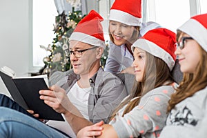 Father reading book for family at home during Christmas