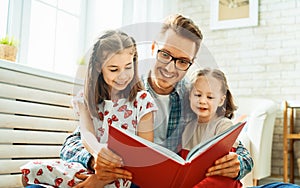 Father reading a book to his daughters