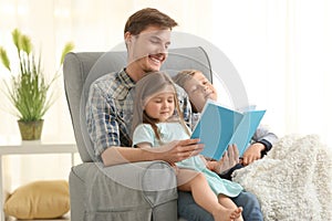 Father reading book to his sleepy children at home