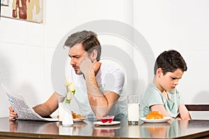 Father reading newspaper and offended son