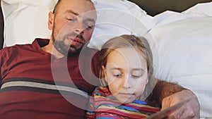 Father reads a bedtime story to his daughter.