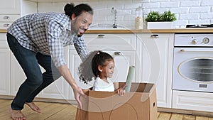 Father riding daughter while she sitting inside of cardboard box