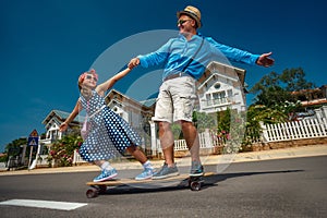 Father riding skateboard with his daughter