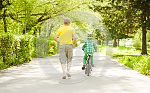 Father run with little boy, who rides a bike