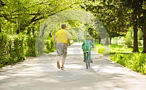 Father run with little boy, who rides a bike