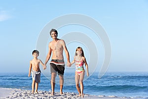 Father Running With Children Along Sandy Beach