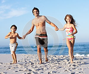 Father Running With Children Along Sandy Beach