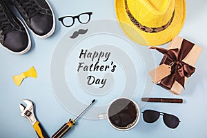 Father`s day background or card Tools Yellow hat Glasses Sneakers Cup of coffee Cigar Gift on a blue background Text Flat lay Top