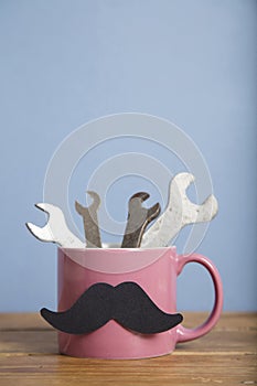 Father`s day background. Coffee mug with tools and a mustache