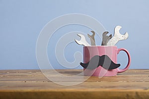 Father`s day background. Coffee mug with tools and a mustache